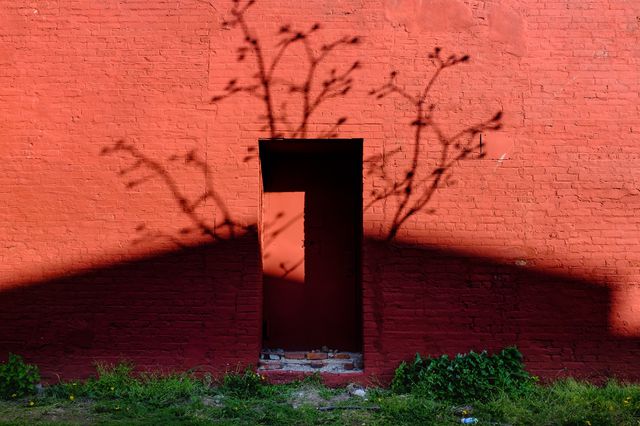 A photo of a red building in Red Hook draped in shadows
